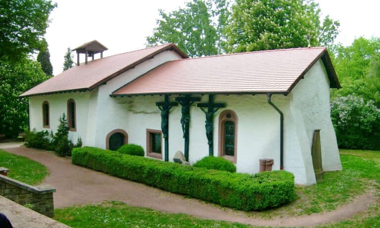 Alte Kirche im Grünen mit Bäumen und gepflegtem Garten, ruhige Atmosphäre.