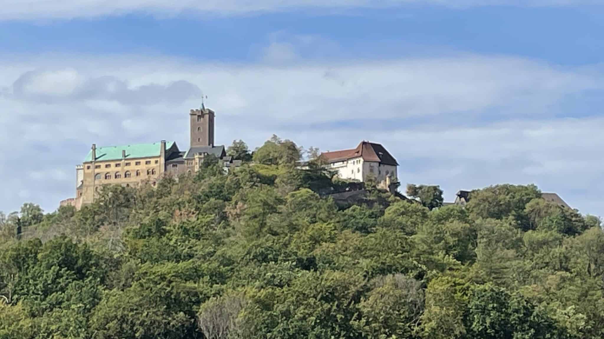 Burg auf einem grünen Hügel bei sonnigem Himmel.