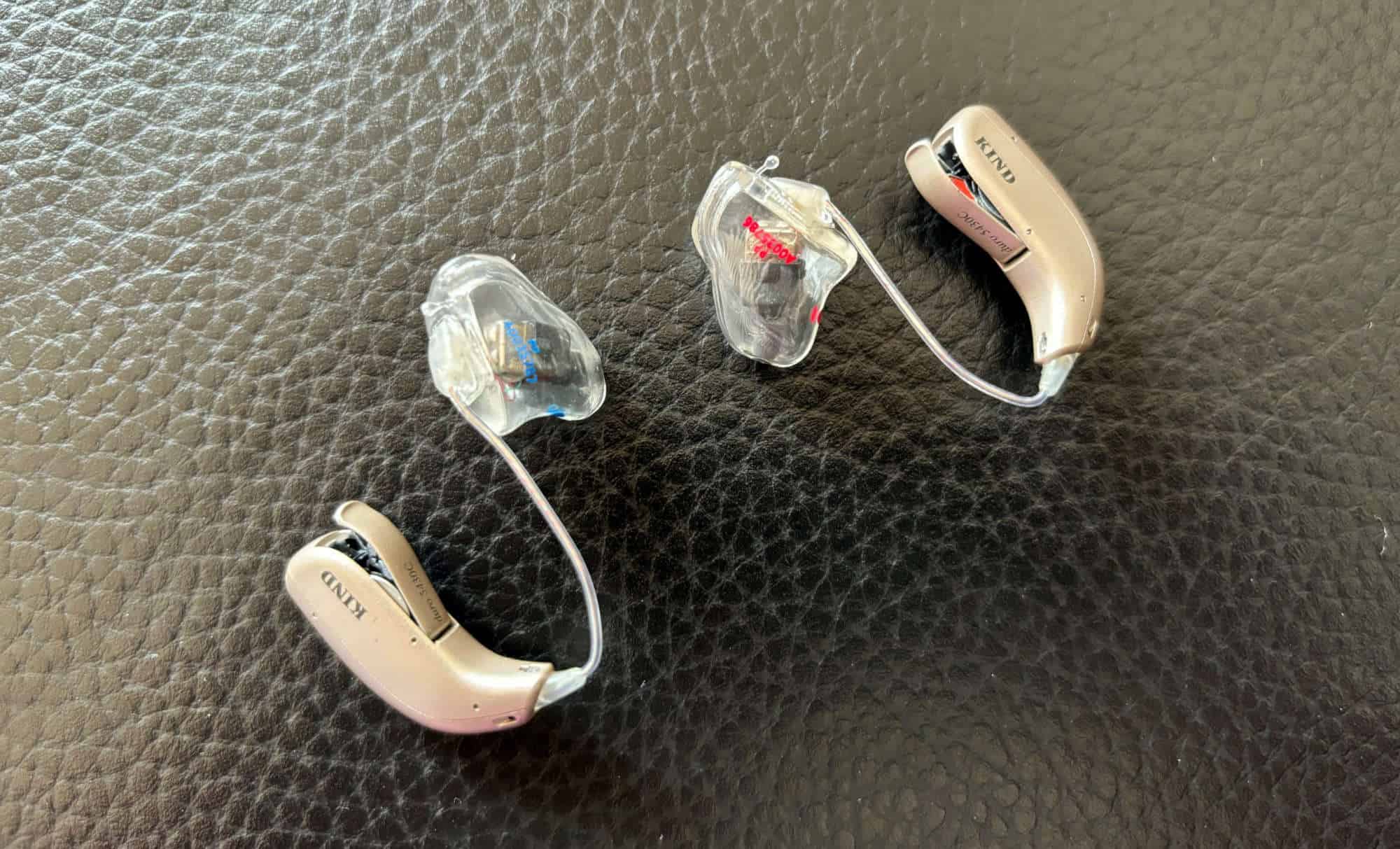 Gehörgeräte auf schwarzem Lederuntergrund, symbolisieren Unterstützung für Schwerhörige.