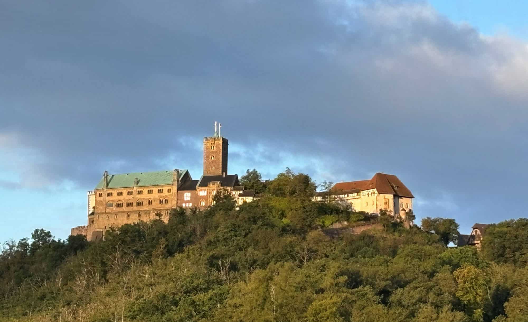 Wartburg auf einem Hügel mit bewölktem Himmel im Hintergrund.