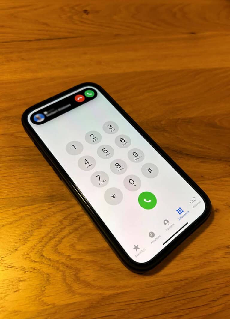 Smartphone mit Wähltastatur auf Holzoberfläche.