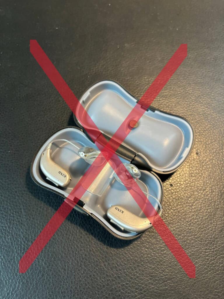 Hörgeräte in Aufbewahrungsbox mit rotem Kreuz.