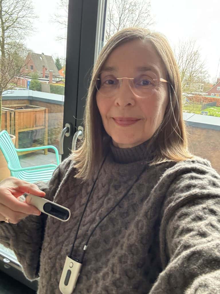 Ich traue mich! Frau mit Hörgerät vor Fenster, zeigt Selbstvertrauen und Mut.