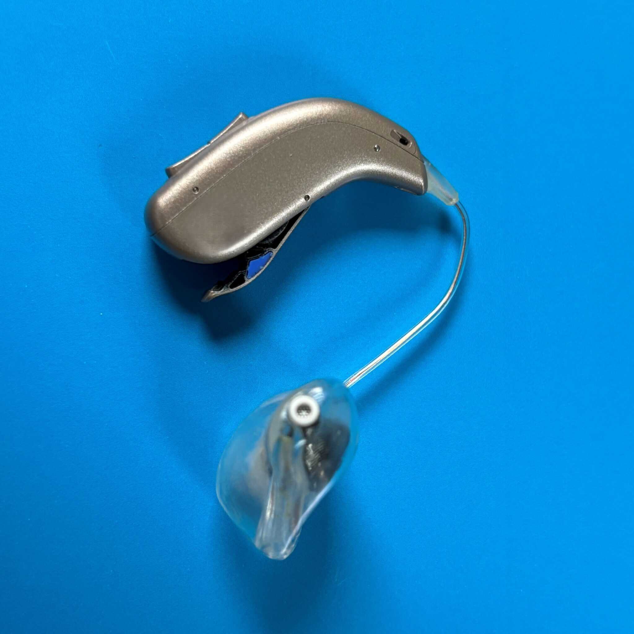 Hörgerät auf blauem Hintergrund, symbolisiert Unterstützung für Schwerhörige.