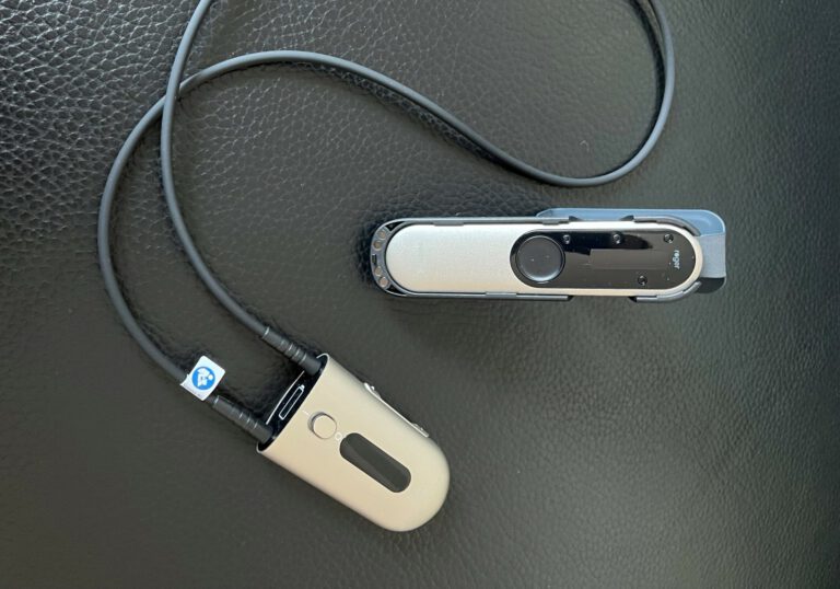 Hörgerät und Aufnahmegerät auf schwarzer Oberfläche.