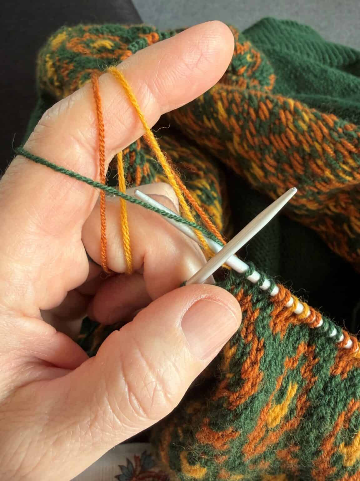 Frau strickt bunte Wollsocken mit Nadel und bunten Garnen.
